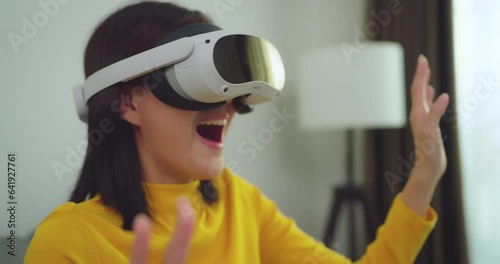 Beautiful asian woman relaxing and playing VR goggles and using futuristic tablet at home. the concept of metaverse, versual reality, future, technology, and internet of things. photo