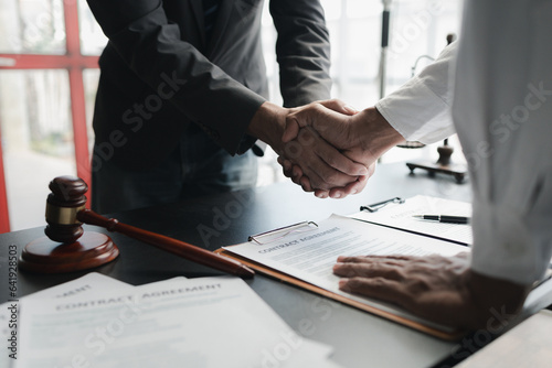 Two lawyers shake hands in a brainstorming meeting. Lawyers search for legal information together to plan how to represent clients in cases, applying the law fairly and honestly. Lawyer concept. photo