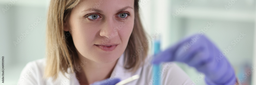 Woman chemist looking at test tube with blue liquid in laboratory Woman chemist looking at test tube with blue liquid in laboratory