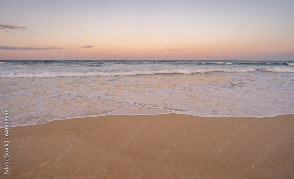 The surf and colorful sky at dusk along Kawana beach on the Sunshine Coast, Queensland, just before the Blue Moon rises above the horizon along the east coast of Australia 2023