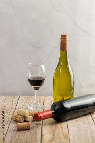 Chilean wine, national day. Bottle of white and red wine, on wooden table, glass, corks, basket. Vertical, with copy space