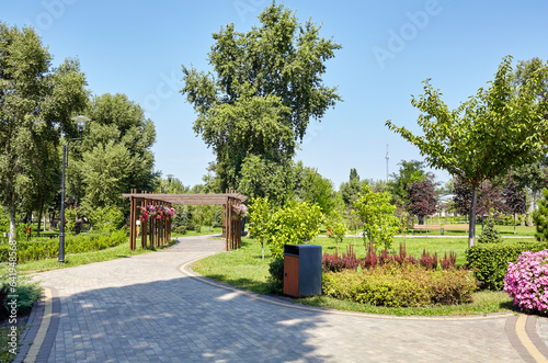 Fototapeta Naklejka Na Ścianę i Meble -  Pathway surrounded by trees and ornamental shrubs in Kyiv, Europe. Recreation place in the city park