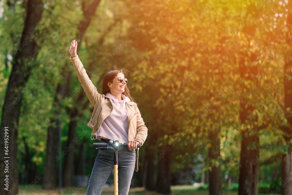 Young woman riding an electric scooter in an autumn park. Green transport, traffic jam problems. Young woman riding an electric scooter in an autumn park. Green transport, traffic jam problems.