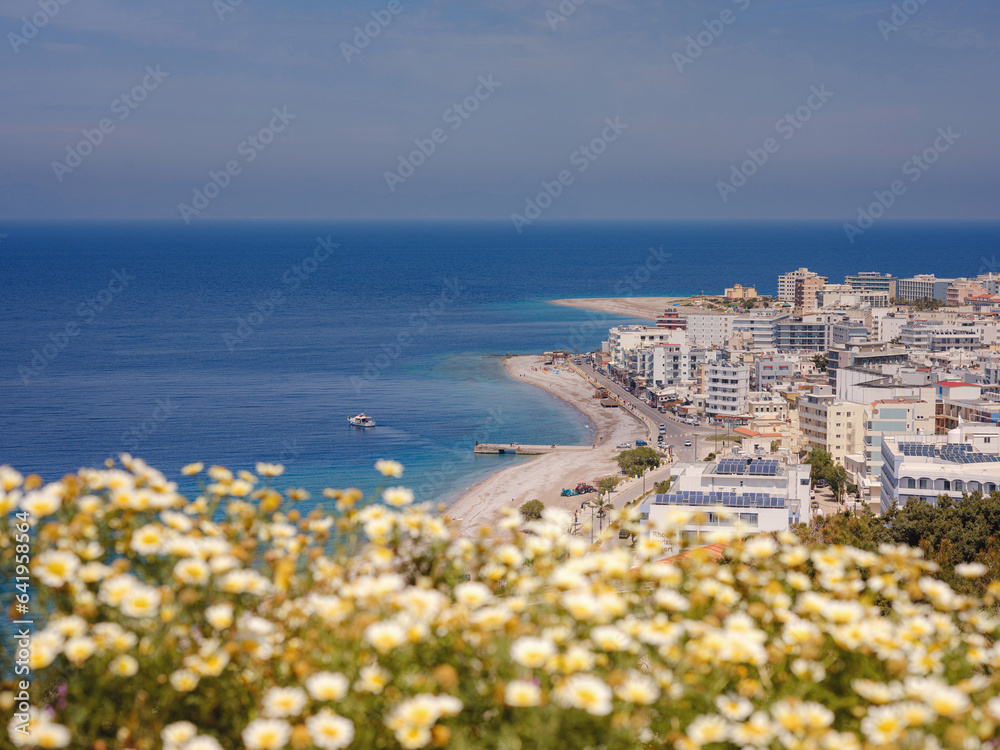 Travel to Greece, Mediterranean islands Rhodes. Aegean beach with sunshades in city of Rhodes view above