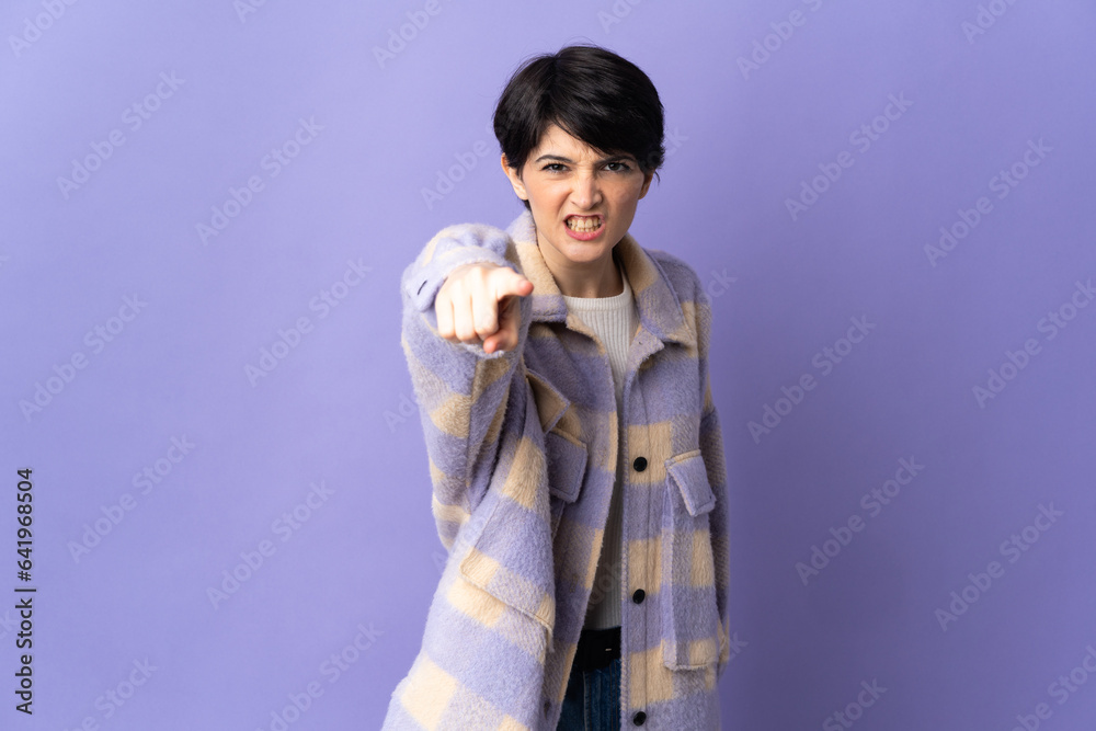 Woman with short hair isolated on purple background frustrated and pointing to the front Woman with short hair isolated on purple background frustrated and pointing to the front