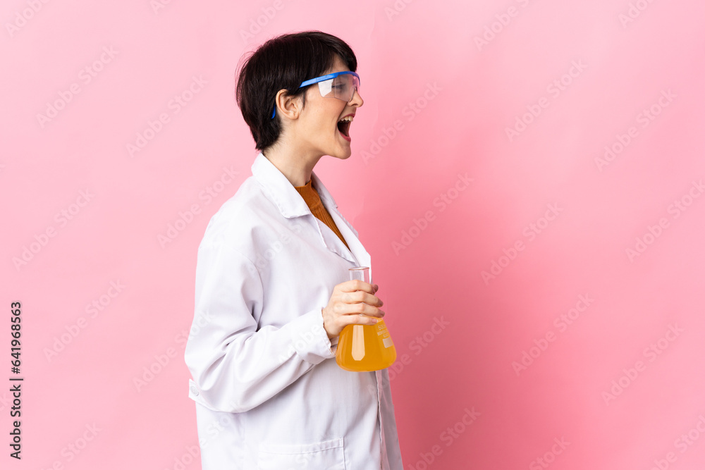 Young scientific woman isolated on pink background laughing in lateral position Young scientific woman isolated on pink background laughing in lateral position