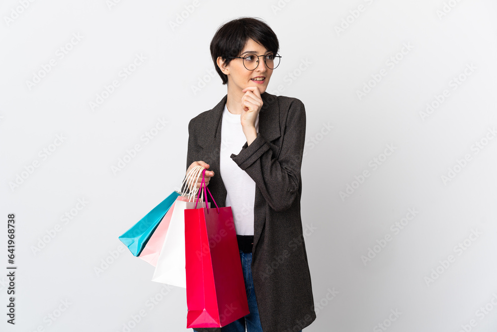 Woman with short hair isolated on white background holding shopping bags and thinking Woman with short hair isolated on white background holding shopping bags and thinking