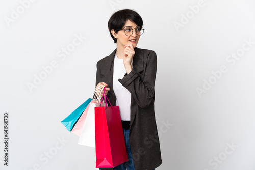 Woman with short hair isolated on white background holding shopping bags and thinking