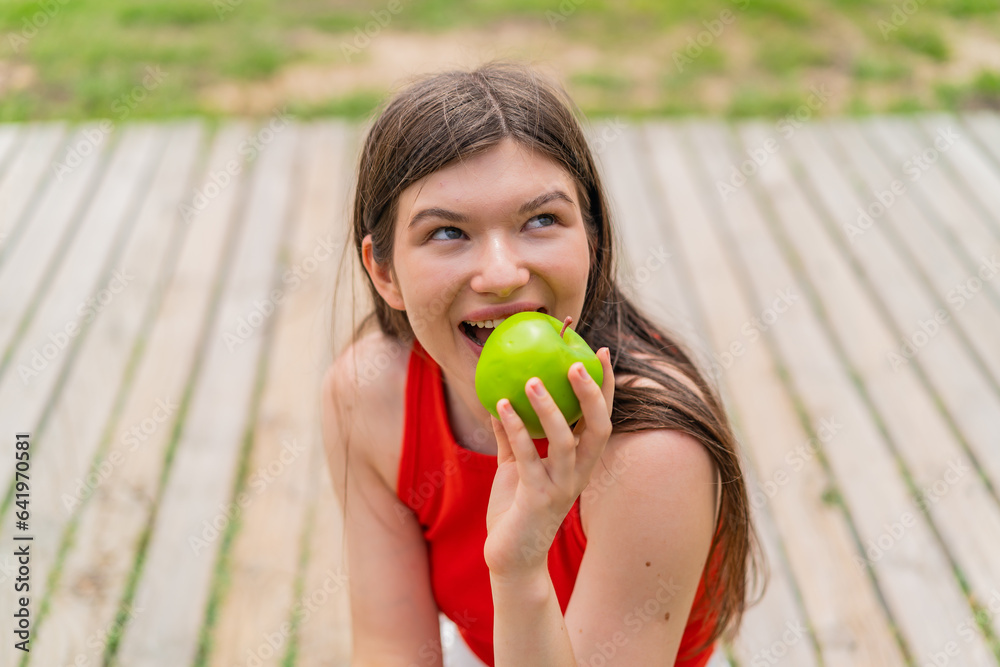 Young pretty woman at outdoors holding an apple Young pretty woman at outdoors holding an apple