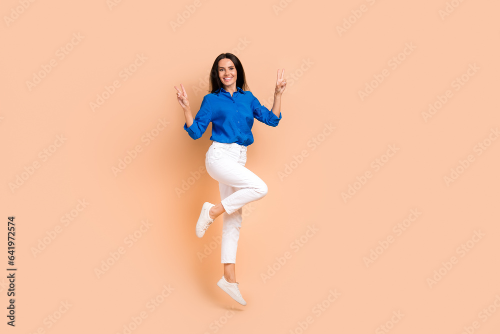 Full length photo of cheerful positive girl wear trendy outfit demonstrate two hands v-sign good mood isolated on beige color background