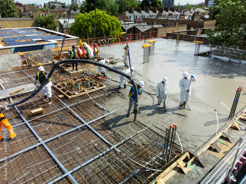 Aerial shot of builders pouring concrete onto roof at building site in London UK