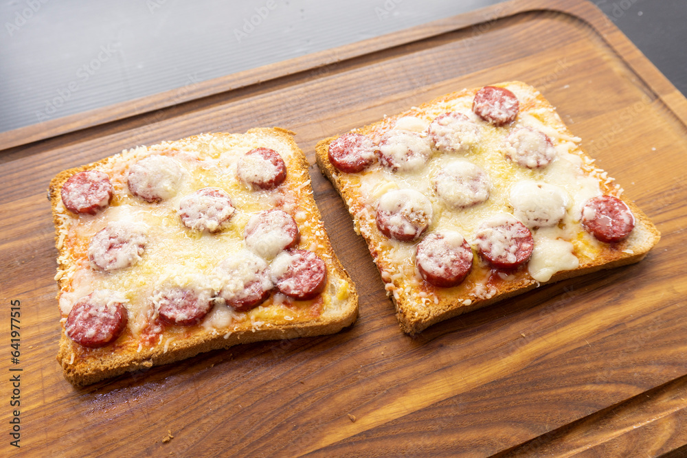 toast with sausages on a wooden background. sandwich. mini pizza. toast with sausages on a wooden background. sandwich. mini pizza.