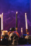 Vertical image of pumpkins, skulls and candles with copy space on purple background