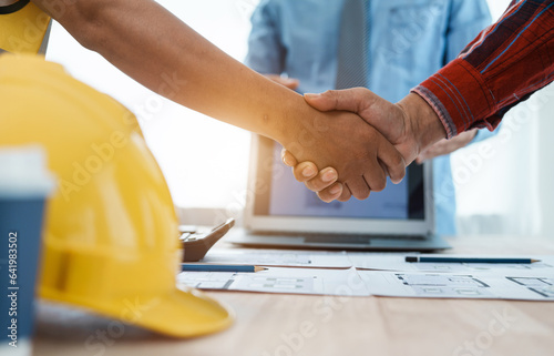 Shaking hands, interracial group of architects and engineers on meeting on blueprint for project work in, construction workers on a construction site
