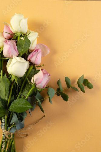 Vertical image of bunch of pink and white rose flowers with copy space on orange background