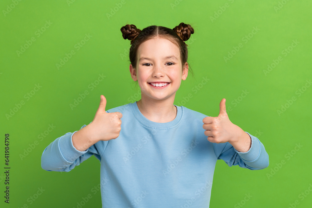 Photo of funny small girl showing thumb fingers up approve agree cool exciting news novelty isolated green color background Photo of funny small girl showing thumb fingers up approve agree cool exciting news novelty isolated green color background