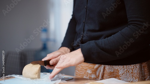 The woman cuts a piece of gingerbread dough