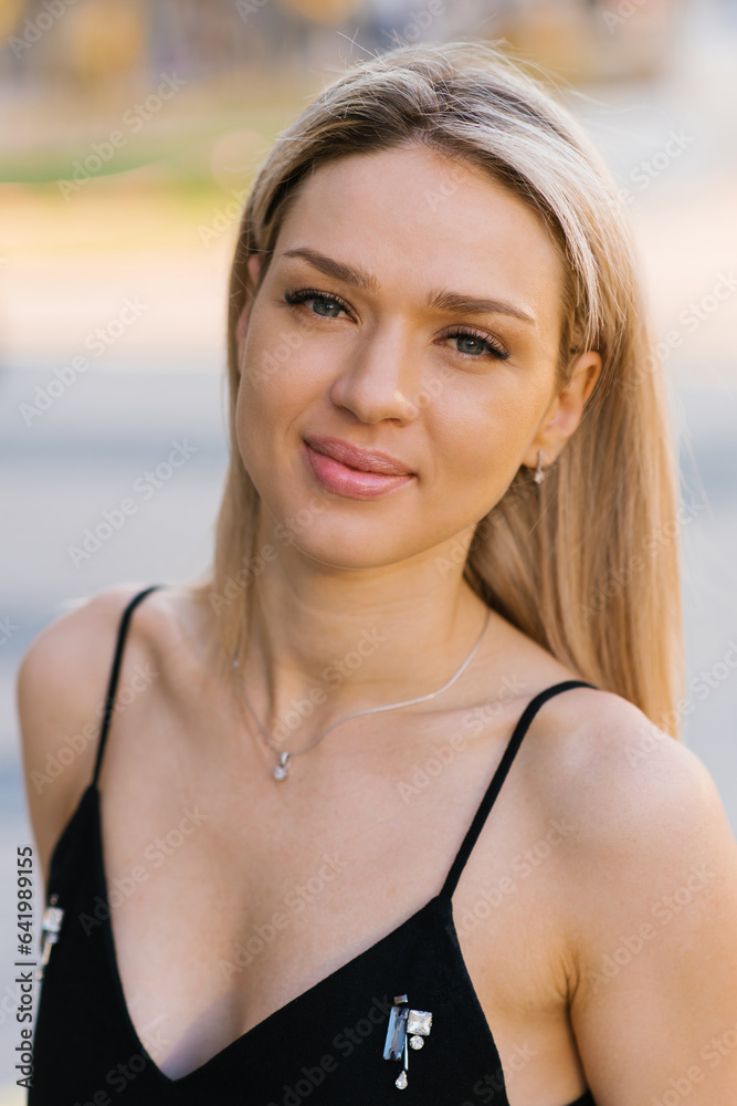 Portrait of a beautiful blonde young woman in a black dress with straps Portrait of a beautiful blonde young woman in a black dress with straps