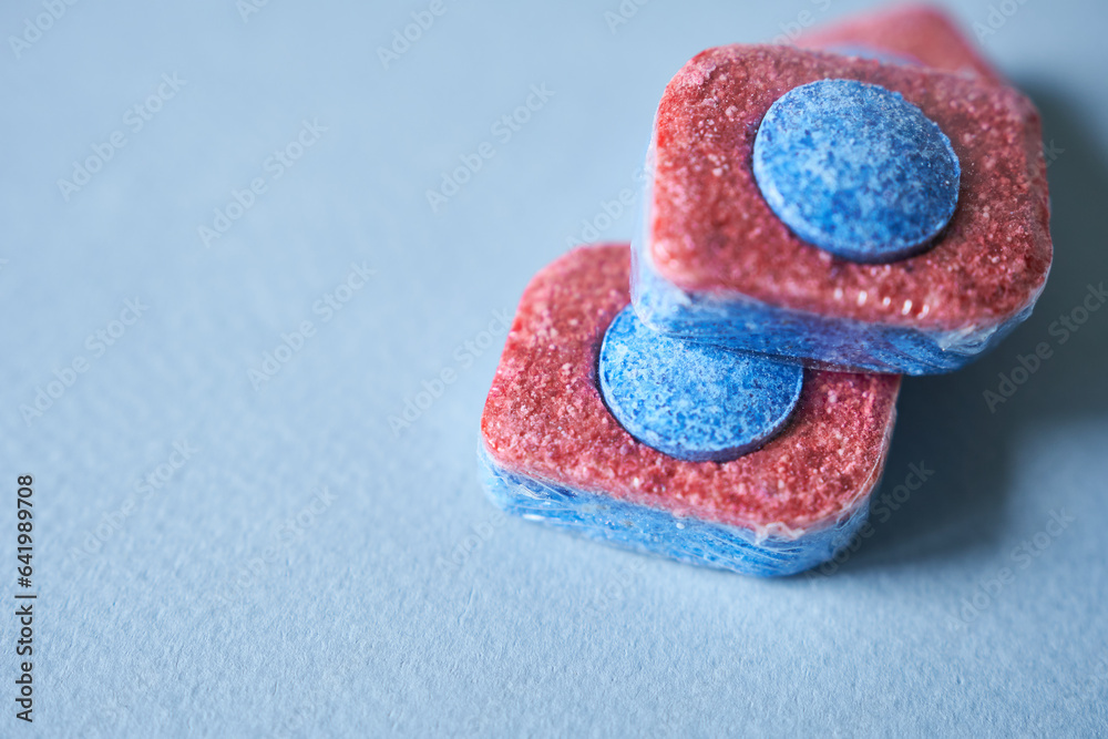 Blue and pink dishwasher pods on blue background. Selective focus. - obrazy, fototapety, plakaty 