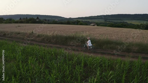 Wallpaper Mural Lone girl in white dress rides bike through rural farmland at golden hour Torontodigital.ca