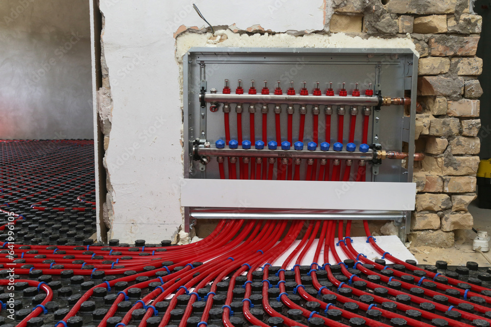 Main control manifold of house heating system, work in progress on construction site for a flat residence building - obrazy, fototapety, plakaty 