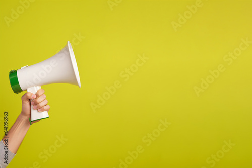 hand holding a megaphone on green background with copy space