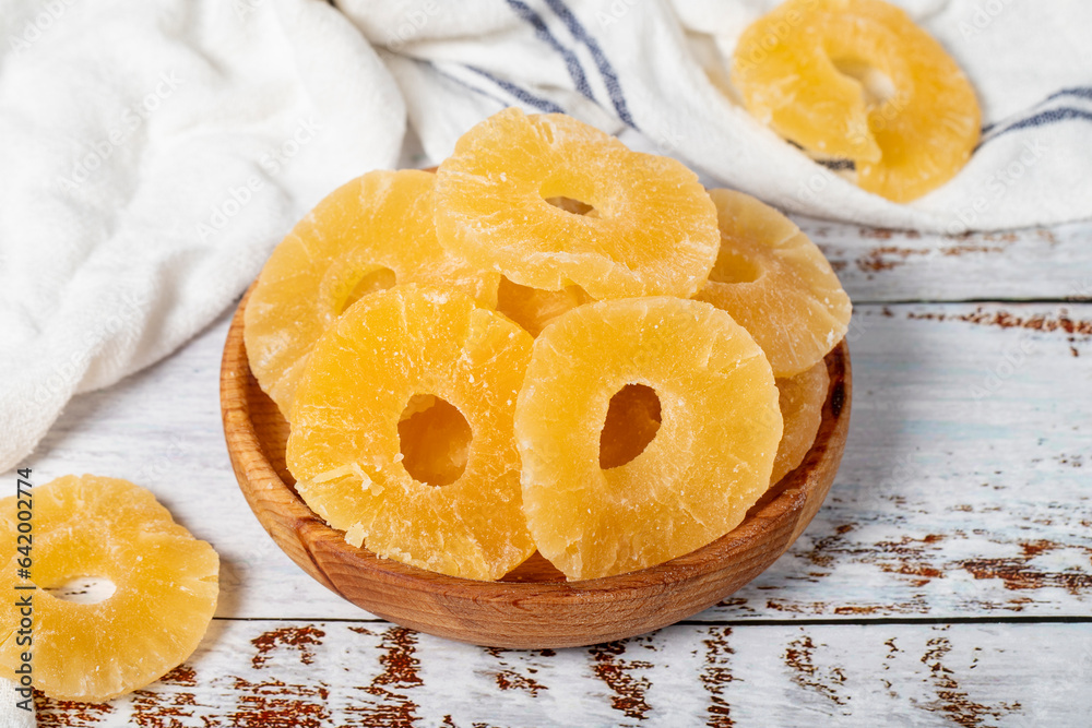 Natural dried pineapple slices in bowl on wooden background. Fruit snack for a health diet and alternative desert. Natural dried pineapple slices in bowl on wooden background. Fruit snack for a health diet and alternative desert.