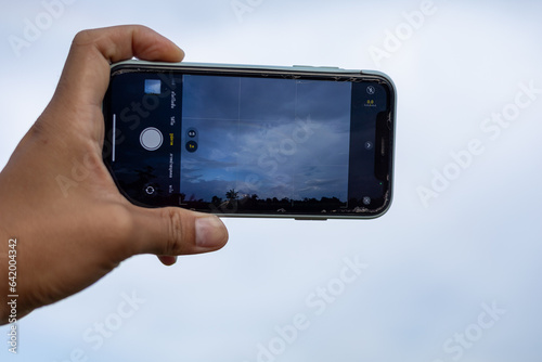 A woman\'s hand holding a phone taking a picture of the scenery
