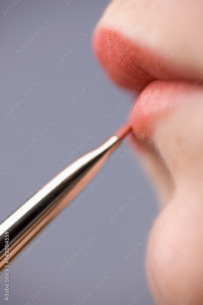 Close up of young woman lips with lipstick brush
