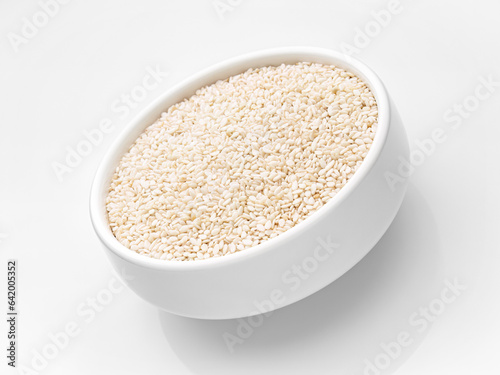  Sesame close-up in a white cup in a tilt on a white background. Close-up. Selective focus. Studio shot. Isolate.