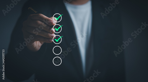 Businessman holding a pen Tick ​​the green correct mark in checkbox, concept of certification checklist, approval document, quality control ,questionnaires or digital document management systems