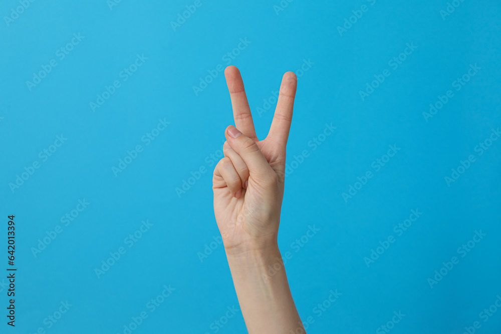 Female hand showing two fingers on a blue background