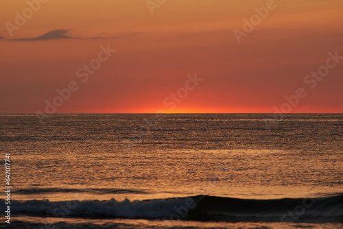 The glowing sun sinking on the horizon of the sea or ocean