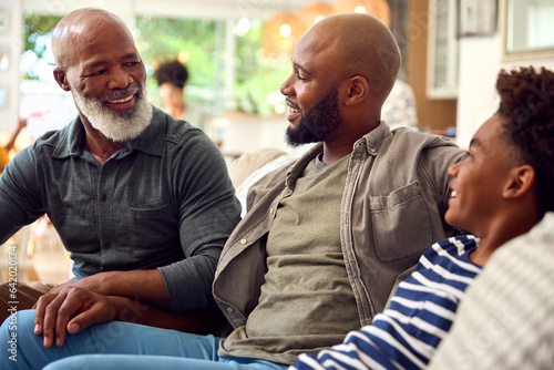 Photos Laughing Multi-Generation Male Family Hanging Out On Sofa At Home Talking Togeth