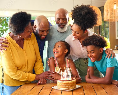 Multi-Generation Family Celebrating Granddaughter's Birthday With Cake And Candles At Home