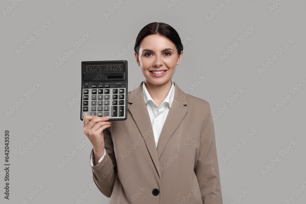 Smiling accountant with calculator on grey background Smiling accountant with calculator on grey background