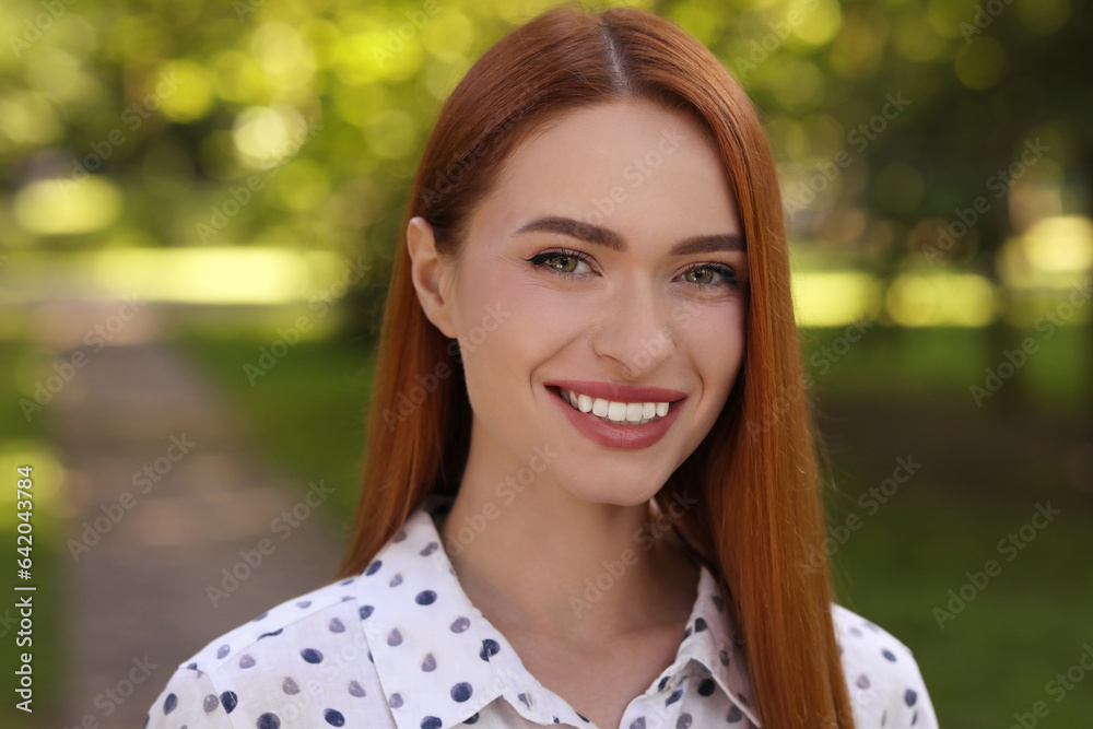 Portrait of charming young woman with beautiful smile in park. Attractive lady posing for camera Portrait of charming young woman with beautiful smile in park. Attractive lady posing for camera
