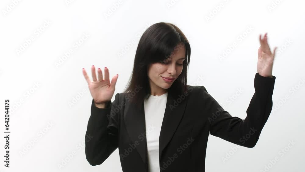 A business woman in a business suit is dancing with an inspired expression on her face. Active young woman having fun on a light background. A business woman in a business suit is dancing with an inspired expression on her face. Active young woman having fun on a light background.