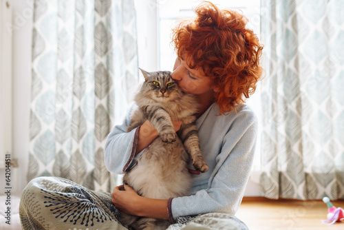 Portrait red-haired curly young woman with beloved fluffy domestic cat