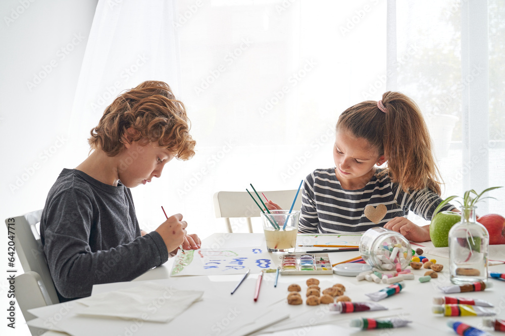 Brother and sister drawing sitting at table Brother and sister drawing sitting at table