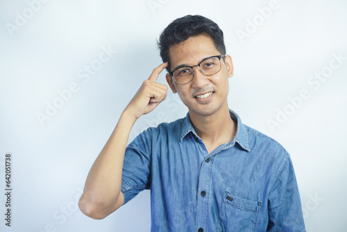Indoor picture of young business man in glasses pictured isolated on white background looking straight at camera, showing confidence and providing stability for employees