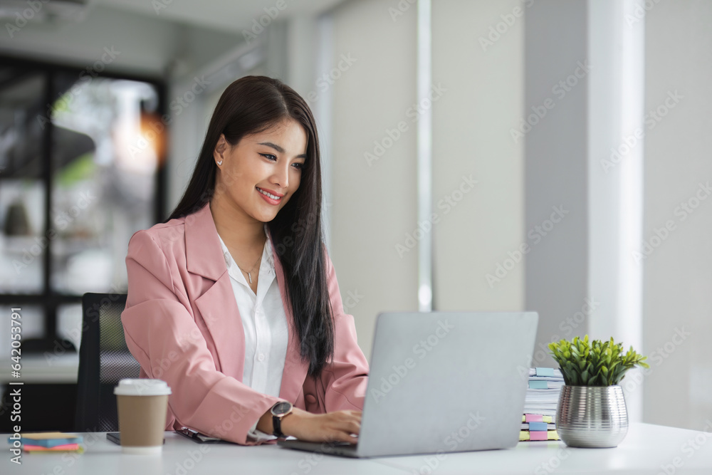 Businesswoman working with laptop computer while having a leisurely cup of coffee at the office in the morning. Businesswoman working with laptop computer while having a leisurely cup of coffee at the office in the morning.