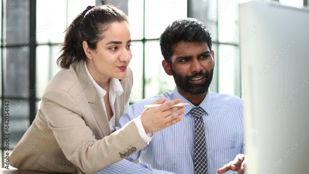 Design professionals using a laptop together in an office Design professionals using a laptop together in an office