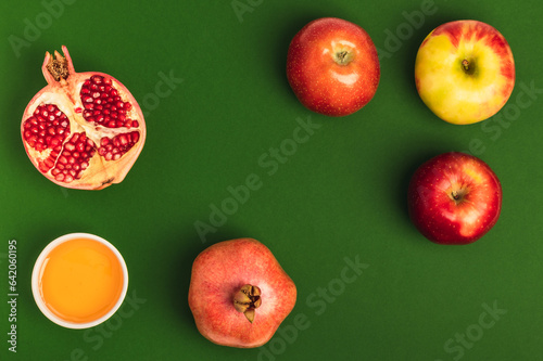 Honey, apples and pomegranates on a green background.Holiday (Rosh Hashanah).Jewish New Year. Flat composition. photo