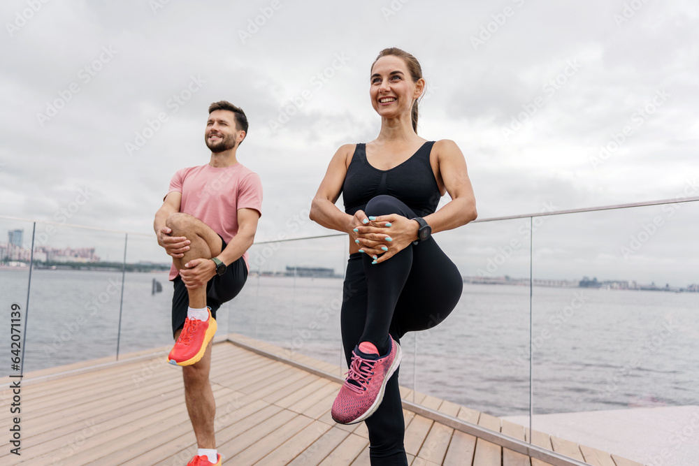 Personal fitness trainer and client fitness training in the fresh air. People use fitness watches and a running app. Friends are a woman and a man in sportswear for sports.