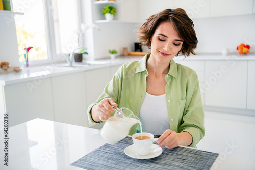 Photo of dreamy adorable lady dressed green shirt preparing latte pouring milk indoors house kitchen