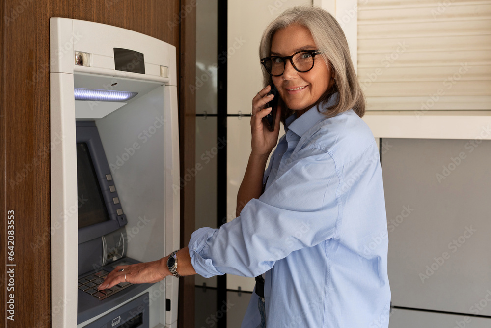 mature adult woman went to the ATM on the street to withdraw cash mature adult woman went to the ATM on the street to withdraw cash