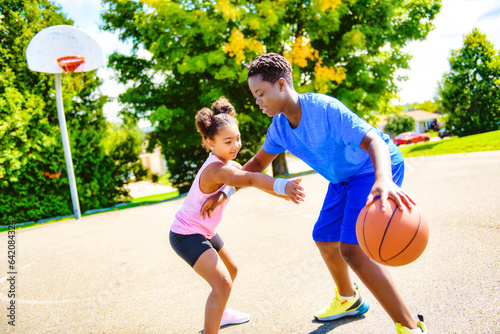 Portrait of brother and sister basketball player standing at basketball court with ball © Louis-Photo
