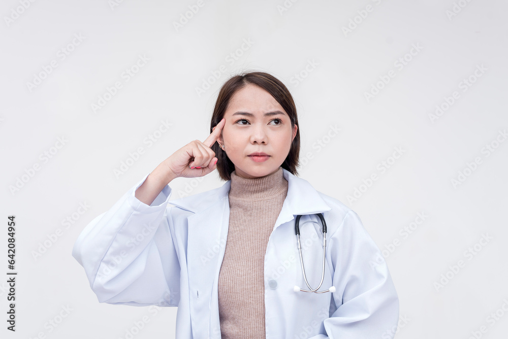 Portrait of a young and skilled doctor, medical student, intern posing while pointing at her head, thinking. Isolated on a white background. Portrait of a young and skilled doctor, medical student, intern posing while pointing at her head, thinking. Isolated on a white background.