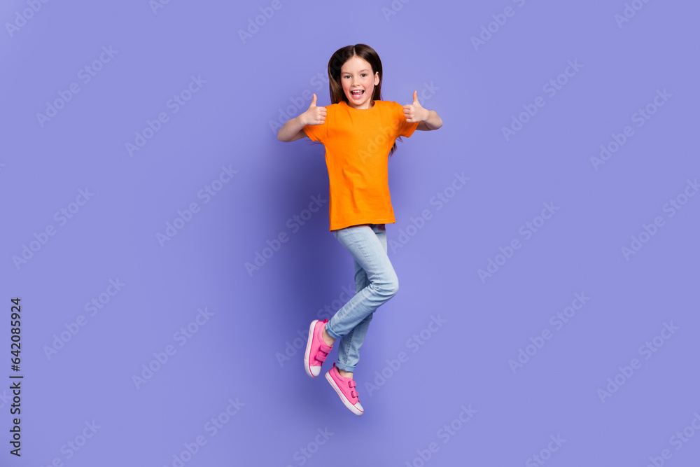 Full length photo of satisfied schoolkid dressed orange t-shirt flying showing thumbs up nice work isolated on purple color background